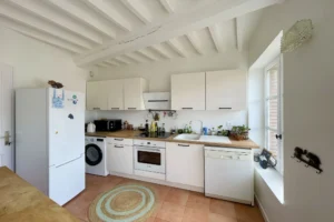 Cuisine équipée avec électroménager intégré, plan de travail en bois et carrelage au sol dans un appartement à vendre à Honfleur.