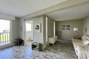 Salon cosy avec cloisons en pavés de verre et vue sur la chambre dans un appartement à Benerville-sur-Mer.