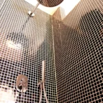 Douche à l’italienne avec carrelage foncé et pommeau pluie dans une salle de bains moderne à Paris 19ᵉ.