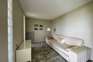 Coin salon avec canapé confortable, sol en bois vieilli et mur décoré dans un appartement à Benerville-sur-Mer.