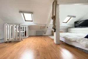 Espace nuit sous les combles avec escalier, coin bureau et lumière naturelle par vélux.
