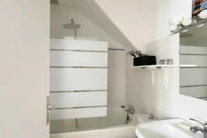 Salle de bains avec baignoire, vasque, rangements et paroi vitrée design.