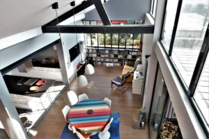 Vue en hauteur sur le séjour du loft à Nanterre, avec coin lecture, verrière atelier et bibliothèque intégrée sur mesure.