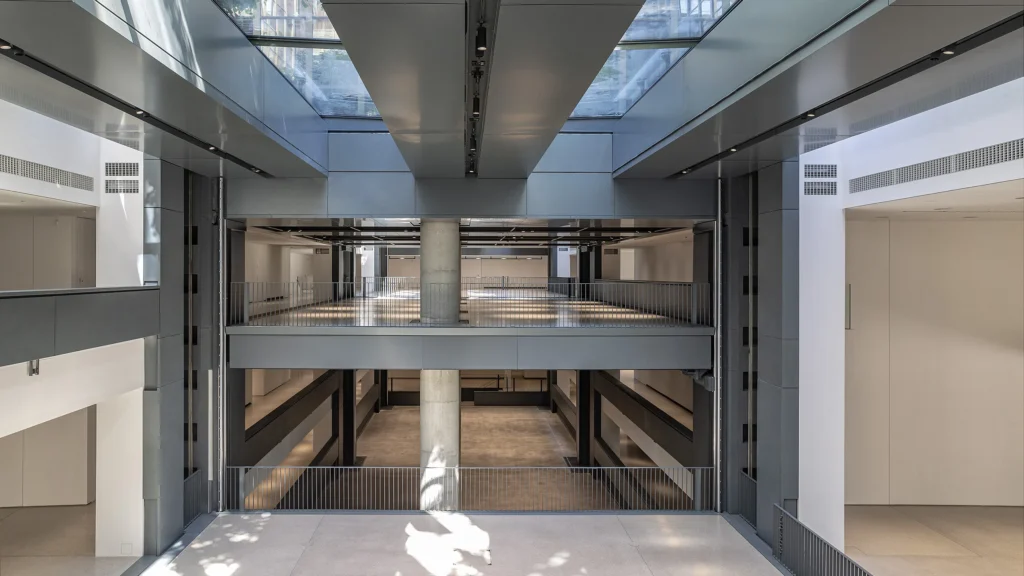 Vue intérieure du nouveau siège de la Fondation Cartier à Paris, avec ses arches en pierre et son escalier suspendu au design contemporain.