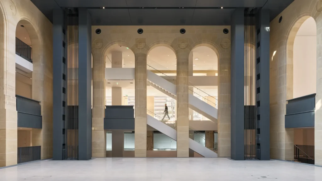 Vue intérieure du nouveau siège de la Fondation Cartier à Paris, avec ses arches en pierre et son escalier suspendu au design contemporain.