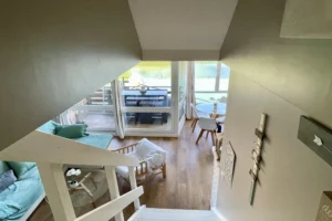 Vue depuis l’escalier de l’appartement en duplex à vendre à Deauville, sur le séjour lumineux et la terrasse donnant sur la marina.