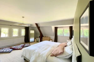 Suite parentale à l’étage avec lit double, lumière traversante, moquette naturelle et fenêtres sur jardin à Ouilly-le-Vicomte.