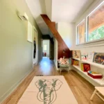 Couloir à l’étage aménagé pour les enfants, avec bibliothèque murale, parquet bois et tapis illustré à Ouilly-le-Vicomte.