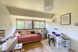 Chambre d’enfant cosy avec lit rose, coin bureau, parquet bois et vue sur le jardin à Ouilly-le-Vicomte.