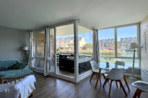 Salle à manger vitrée de l’appartement en duplex à vendre à Deauville, avec vue sur la marina et accès à la terrasse.