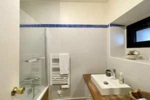 Salle de bain moderne de l’appartement en duplex à vendre à Deauville, avec meuble vasque, baignoire et sèche-serviettes.
