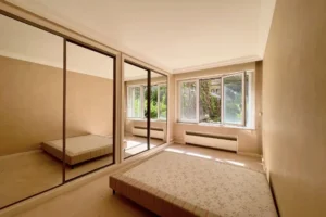 Chambre lumineuse avec grandes fenêtres et placards miroirs intégrés, appartement à vendre Paris 16 avenue Foch.