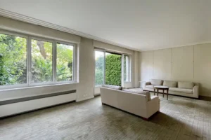 Grand séjour lumineux avec deux canapés et baies vitrées ouvertes sur le jardin particulier, appartement Paris 16 avenue Foch.