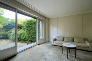 Salon avec canapé et table basse ouvrant sur la terrasse et le jardin particulier, appartement Paris 16 avenue Foch.