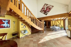 Hall d’entrée spacieux de la maison à vendre à Moisville dans l’Eure avec escalier en bois et murs décorés