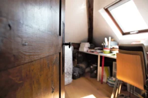 Petit espace bureau sous combles avec fenêtre de toit et poutre apparente, appartement rue de Turenne Paris 3ᵉ.