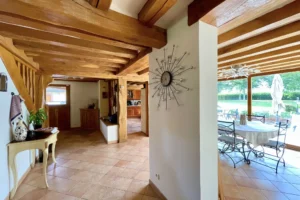 Entrée intérieure de la maison à vendre à Moisville dans l’Eure avec vue sur la véranda et poutres en bois apparentes
