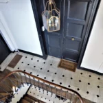 Entrée de l’immeuble avec escalier ancien et carrelage à motifs, vue sur la porte d’accueil rue de Turenne Paris 3ᵉ.