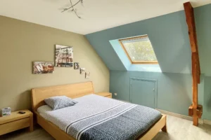 Chambre à l’étage de la maison à vendre à Moisville dans l’Eure avec poutre apparente et fenêtre de toit