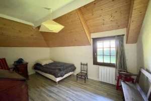 Chambre sous combles avec fenêtre donnant sur le jardin dans une maison normande à Bonneville-la-Louvet.