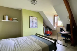 Chambre avec espace bureau à l’étage de la maison à vendre à Moisville dans l’Eure avec poutre apparente et fenêtre sur jardin