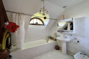 Salle de bains avec baignoire et fenêtre arrondie dans une maison normande à Bonneville-la-Louvet.