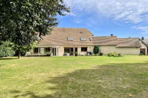 Vue sur la façade arrière de la maison à vendre à Moisville dans l’Eure avec véranda, grandes baies vitrées et vaste jardin