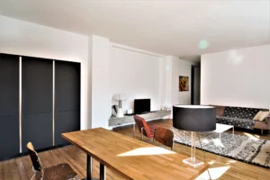 Espace ouvert du loft à Paris 11 Parmentier avec table en bois, rangements noirs intégrés et salon décoré dans un style contemporain.