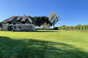 Maison en colombages avec toit de chaume à Bonneville-la-Louvet, offrant un vaste terrain arboré dans le Calvados.