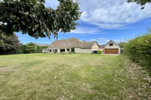 Grand jardin de la maison à vendre à Moisville dans l’Eure avec vue sur le garage indépendant et l’annexe