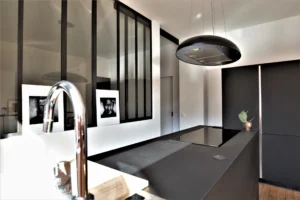 Détail de la cuisine du loft à Paris 11 Parmentier avec îlot noir, verrière atelier et robinet design.