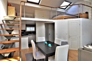 Vue sur la mezzanine avec chambre et cuisine ouverte du loft à Paris 9 Notre-Dame-de-Lorette, avec escalier design et salle à manger.