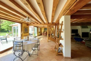 Séjour lumineux de la maison à vendre à Moisville dans l’Eure avec poutres en bois apparentes, coin repas et accès direct au jardin