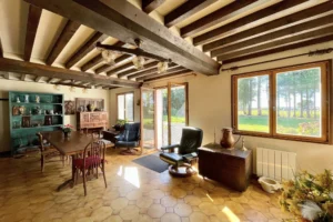 Salle à manger lumineuse avec poutres apparentes et accès direct au jardin dans une maison normande à Bonneville-la-Louvet.