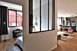 Chambre du loft à Paris 11 Parmentier avec verrière intérieure et parquet ancien.