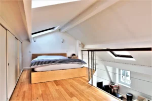 Chambre en mezzanine du loft à Paris 9 Notre-Dame-de-Lorette, avec parquet bois, rangements intégrés et lumière zénithale.