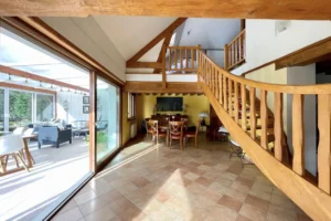 Espace de vie lumineux de la maison à vendre à Moisville dans l’Eure avec accès à la véranda et escalier en bois