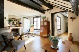Salon lumineux avec poutres apparentes et parquet en chêne, au cœur du quartier Montorgueil à Paris 2, appartement de caractère proposé par Quality Street Immobilier.