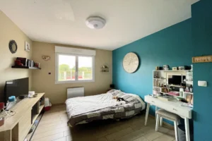 Chambre aménagée à Le Torquesne 14130, aux tons clairs et mur bleu canard, pouvant également servir de bureau, avec vue dégagée sur la campagne du Calvados.