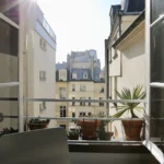 Vue dégagée sur les toits parisiens depuis la fenêtre d’un appartement lumineux à Paris 2, quartier Montorgueil.