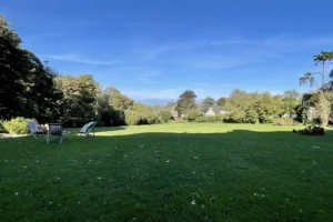 Vue mer depuis le parc du château de Villers-sur-Mer, vaste pelouse bordée d’arbres avec transats, offrant un cadre verdoyant et paisible dans le Calvados.