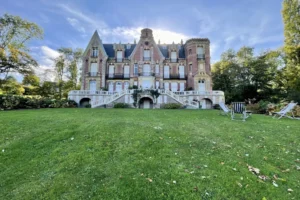 Vue d’ensemble du château de Villers-sur-Mer avec son vaste jardin verdoyant et ses transats, dans un cadre calme et arboré du Calvados.