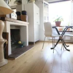 Salle à manger lumineuse avec cheminée décorative, grandes fenêtres ouvertes et parquet en chêne dans un loft à Paris 2 Montorgueil.