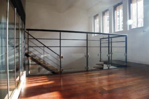 Mezzanine vitrée d’un loft à Paris 19, entre Belleville et les Buttes Chaumont, avec garde-corps en métal et escalier contemporain sur parquet en bois massif.