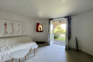 Pièce de vie lumineuse avec accès direct au jardin du château de Villers-sur-Mer, décorée simplement avec canapé, tables basses et ouverture sur la verdure du Calvados.