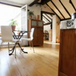 Salle à manger baignée de lumière avec parquet en bois clair, poutres apparentes et mobilier vintage dans un loft à Paris 2 Montorgueil.