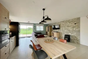 Séjour lumineux avec cuisine ouverte à Le Torquesne 14130, décoration moderne avec mur en pierre et vue sur le jardin du Calvados.