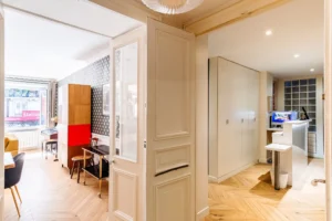 Vue depuis l’entrée sur la circulation centrale de l’appartement, parquet en chevron et mobilier contemporain, Paris 10 – Gare de l’Est.