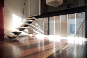 Escalier design en métal et bois d’un loft à Paris 19, Villa Marcel Lods, illuminé par la lumière naturelle sur parquet en chêne et verrière industrielle.