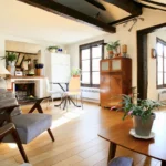 Salon lumineux au charme parisien avec poutres apparentes, mobilier vintage et parquet clair dans un appartement du quartier Montorgueil à Paris 2.